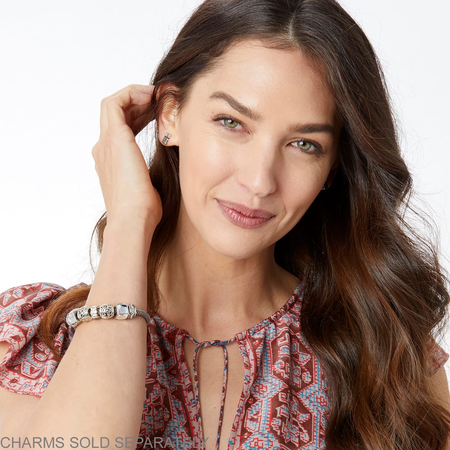 Model wearing a Brighton silver-plated charm bracelet with ornate beads and crystal accents on woven band