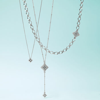 Brighton layered necklaces with silver-plated diamond-shaped pendants featuring crystal accents and varied chain styles on a white background