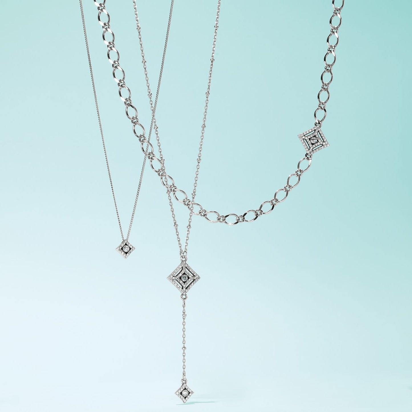 Brighton layered necklaces with silver-plated diamond-shaped pendants featuring crystal accents and varied chain styles on a white background