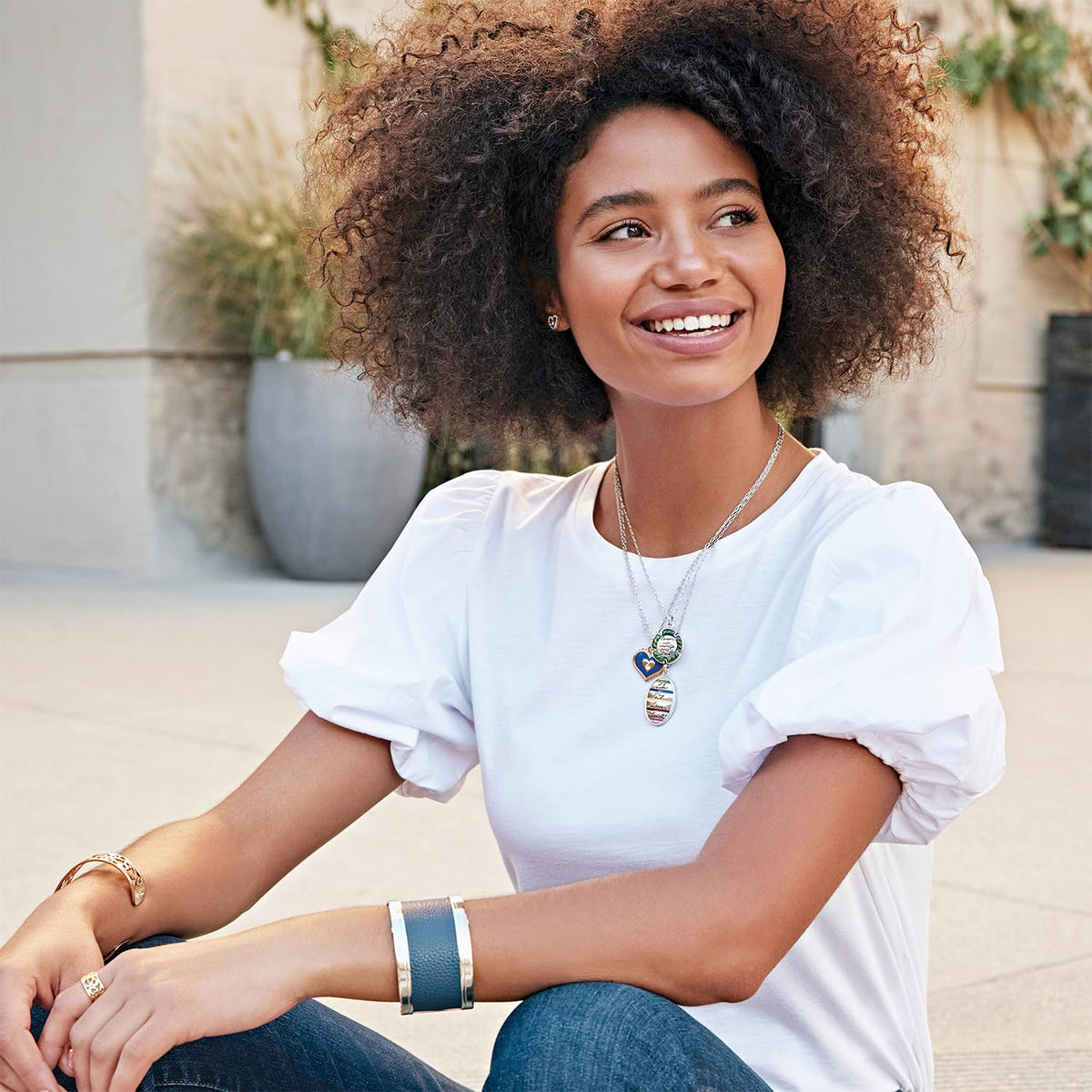 Model wearing a Brighton silver-plated layered pendant necklace with blue and green enamel charms and coordinating Brighton accessories