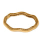 Brighton bangle bracelet shown from the back with wavy gold-tone openwork design and hinged clasp on a white background