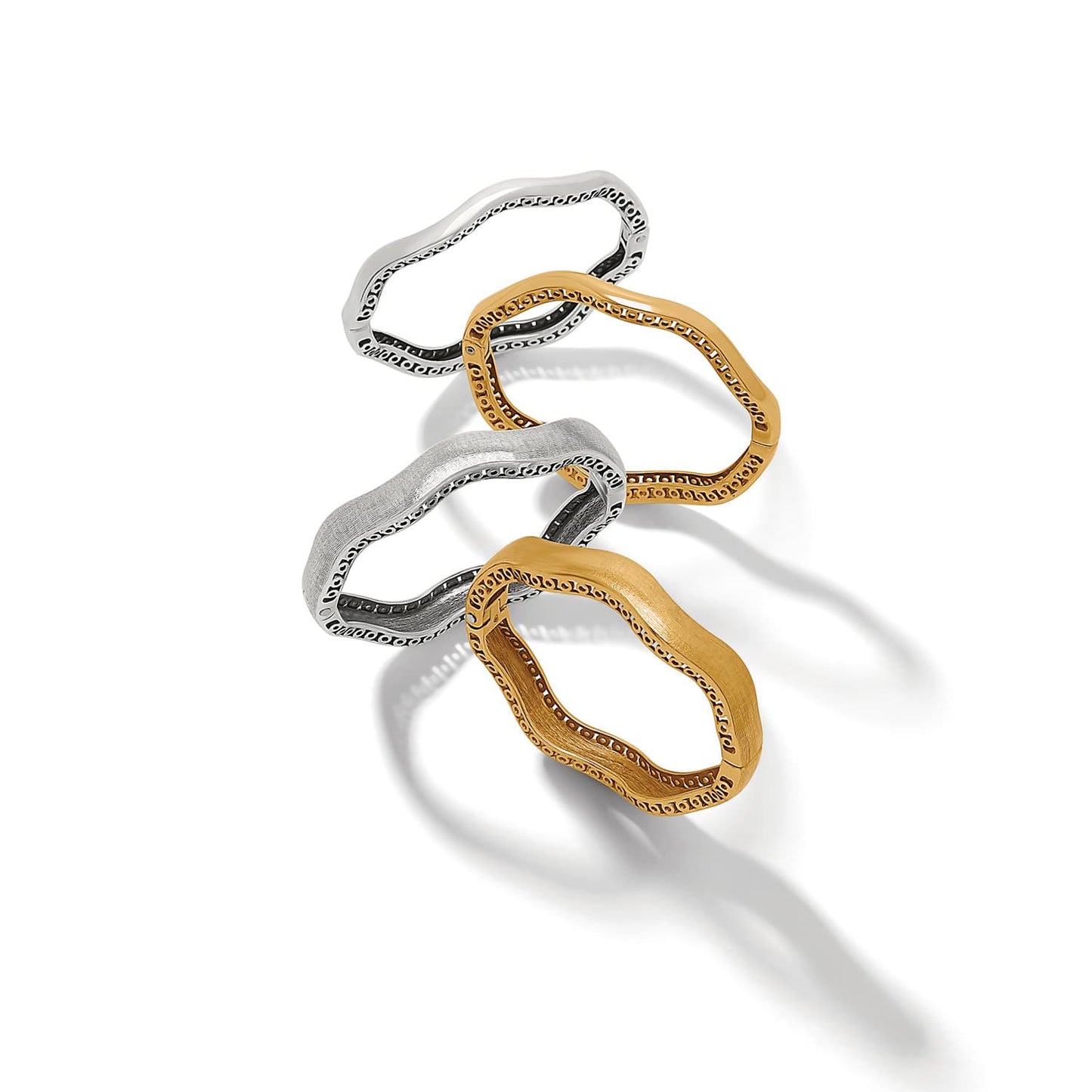 Brighton wavy bangle bracelets in silver-plated and gold-tone finishes with scrollwork interior detailing on a white background