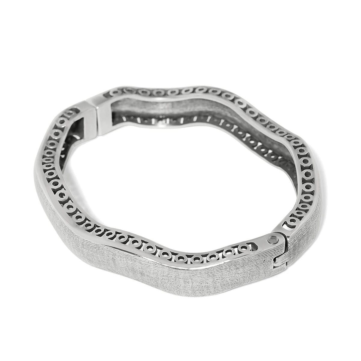 Brighton bangle bracelet with silver-plated wavy design, textured exterior, and scrollwork openwork along inner edge on a white background