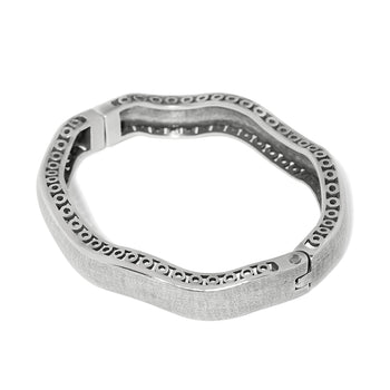 Brighton bangle bracelet with silver-plated wavy design, textured exterior, and scrollwork openwork along inner edge on a white background