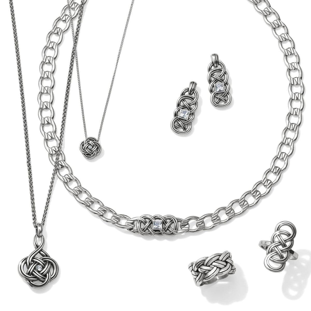 Brighton silver-plated jewelry set styled with matching necklaces, earrings, and knot-detail rings featuring crystal accents on white