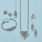 Brighton silver-plated jewelry set styled with Celtic knot heart pendants and coordinating pieces on a blue background