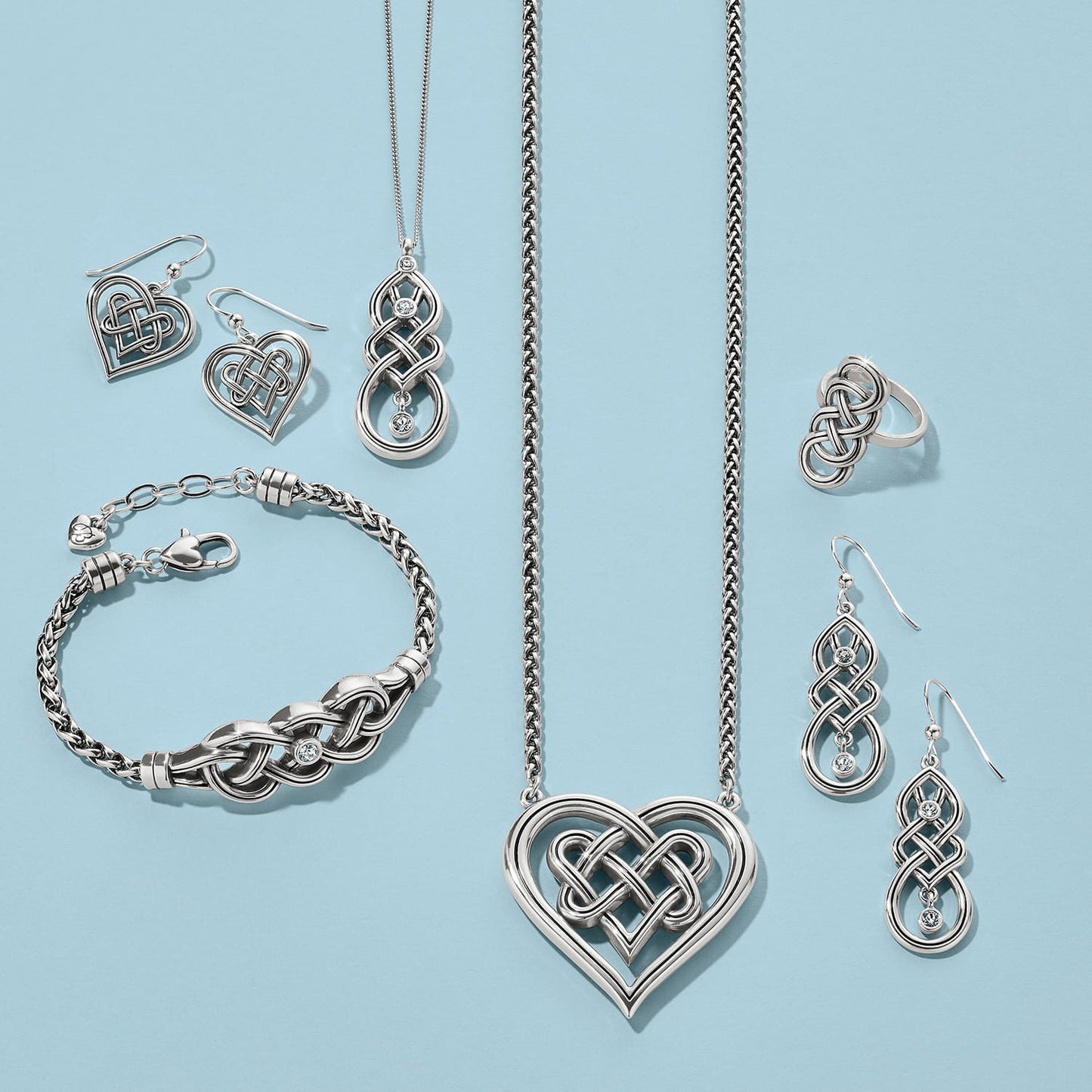 Brighton silver-plated jewelry set styled with Celtic knot heart pendants and coordinating pieces on a blue background