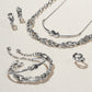 Brighton silver-plated jewelry set styled with knotted bracelet, necklace, earrings, and ring on a neutral woven background
