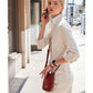 Model with a Brighton red leather crossbody handbag featuring braided strap and woven trim details