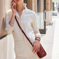 Model with a Brighton red leather crossbody bag featuring braided strap and trim, styled with coordinating Brighton accessories