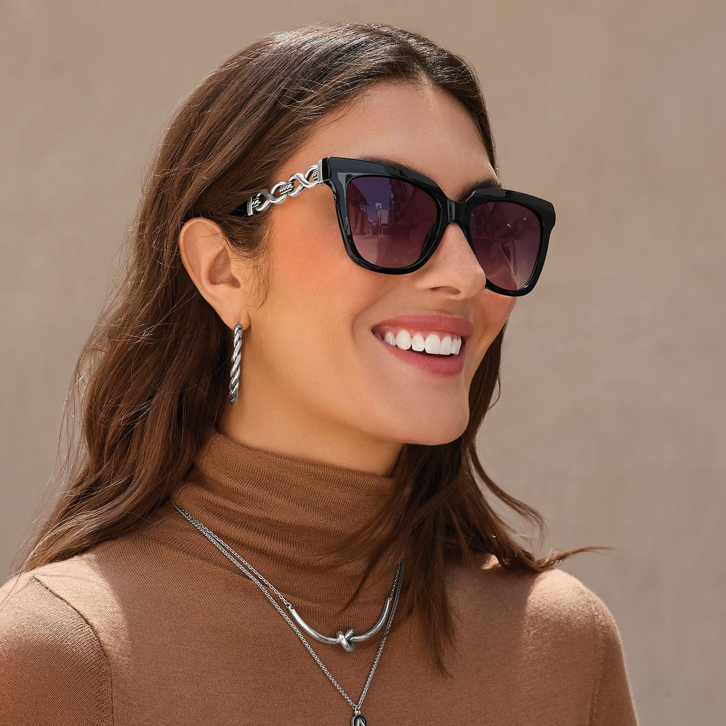 Model wearing Brighton black square sunglasses with silver-tone chain-link detail on the temples, styled with silver jewelry
