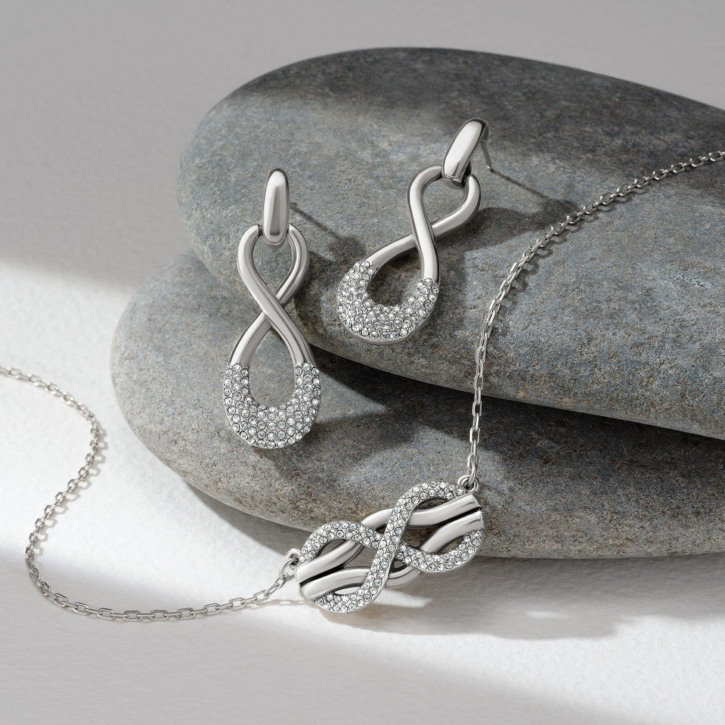 Brighton silver-plated infinity necklace and matching drop earrings with crystal accents styled with smooth gray stones