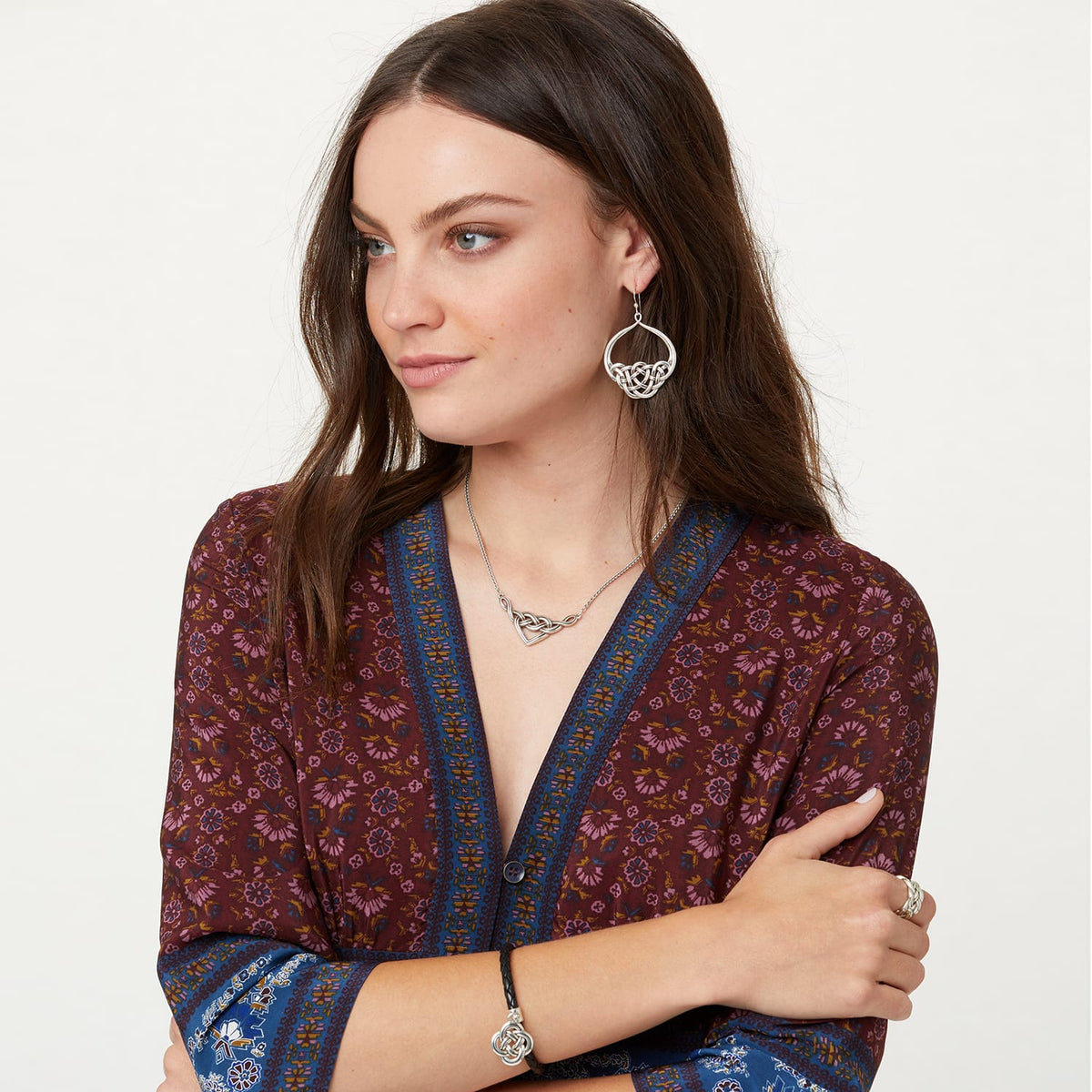 Model wearing Brighton silver-plated Celtic knot drop earrings paired with a matching interwoven heart pendant necklace