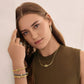 Model wearing a Brighton gold-tone knot necklace with coordinating Brighton accessories including hoop earrings and stacked bangles