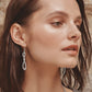 Model wearing Brighton silver-plated drop earrings with an infinity-shaped design and French wire hooks