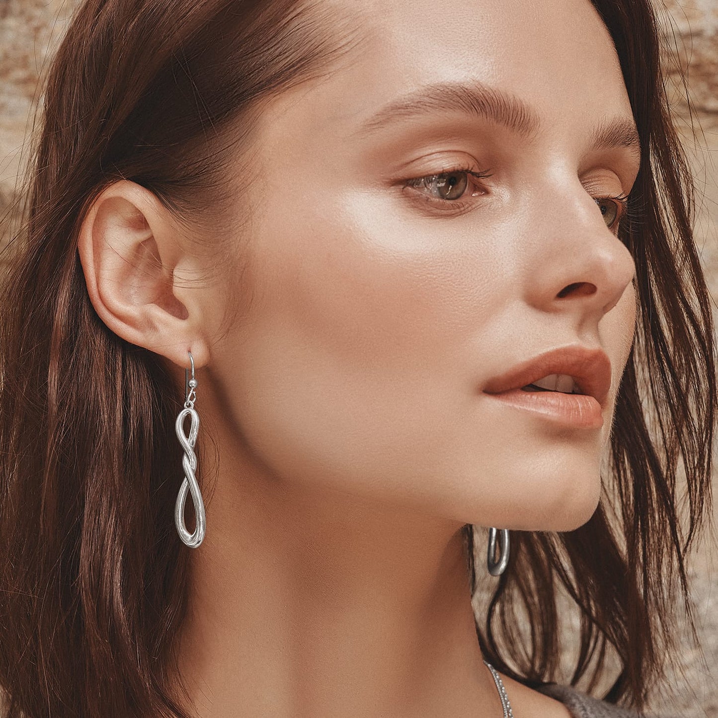 Model wearing Brighton silver-plated drop earrings with an infinity-shaped design and French wire hooks