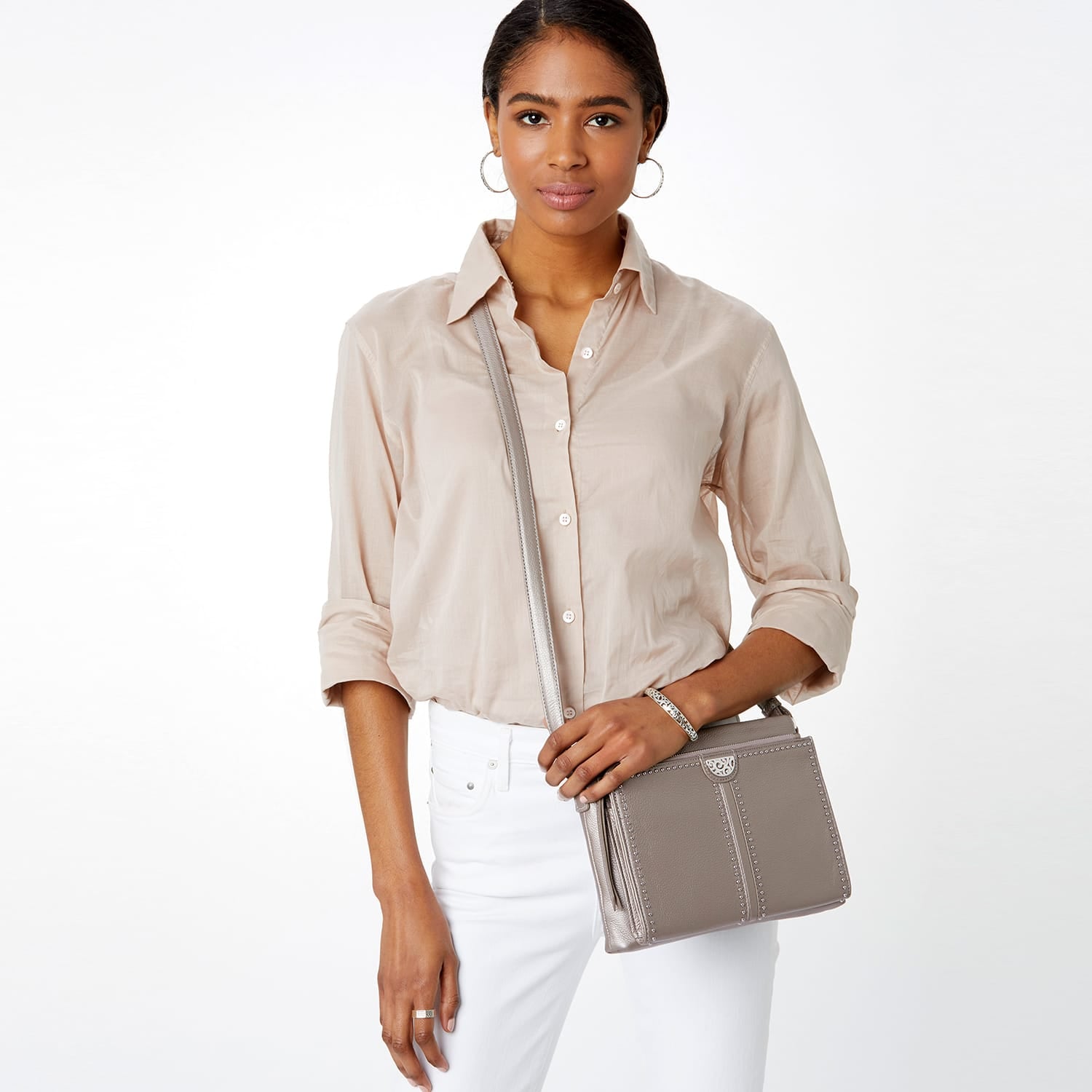 Model with a Brighton taupe leather crossbody handbag with silver-tone stud detailing and matching shoulder strap