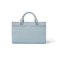 Brighton handbag shown from the back in light blue pebbled leather with rolled top handles on a white background