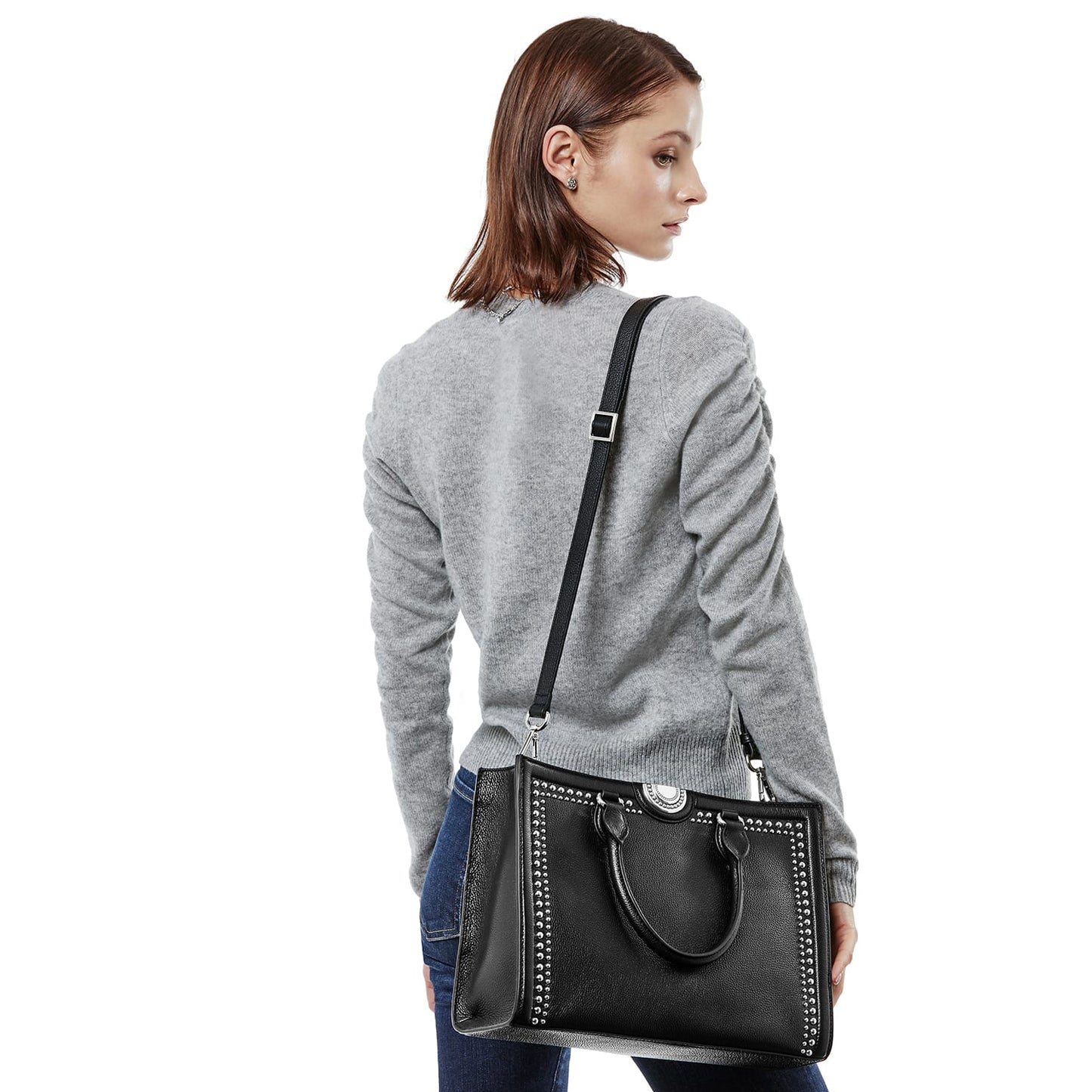 Model with a Brighton black studded handbag featuring silver-tone stud trim, top handles, and adjustable shoulder strap