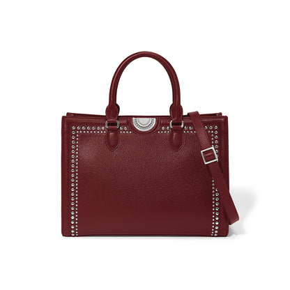 Brighton burgundy leather handbag with silver-tone studded trim, medallion accent, and adjustable crossbody strap on a white background