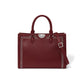 Brighton burgundy leather handbag with silver-tone studded trim, medallion accent, and adjustable crossbody strap on a white background