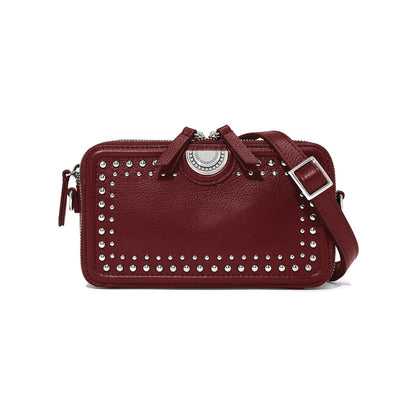 Brighton burgundy leather crossbody handbag with silver-tone studs, medallion accent, and adjustable strap on a white background