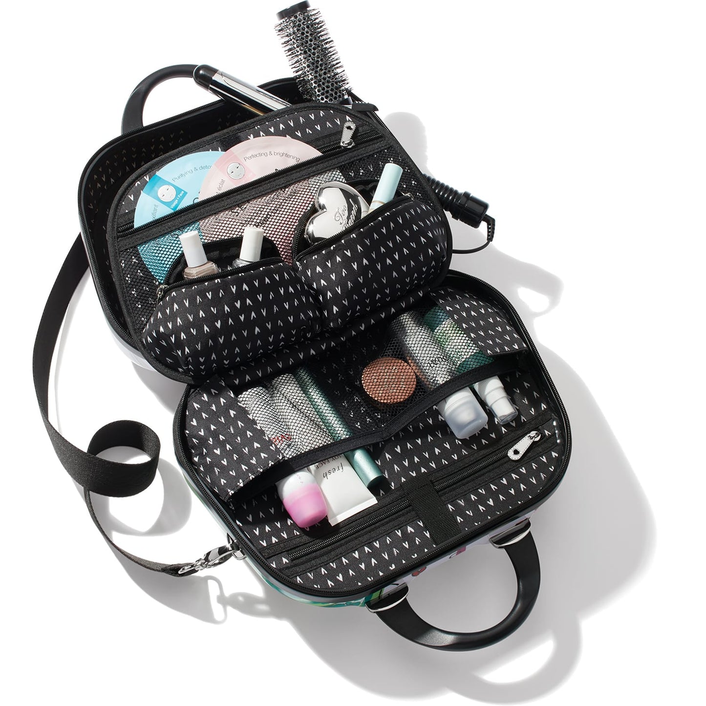 Brighton travel cosmetic case shown open with heart-print interior holding brushes, bottles, and beauty items on a white background