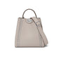Brighton handbag in taupe leather with silver-tone studded trim, top handle, and adjustable crossbody strap on a white background