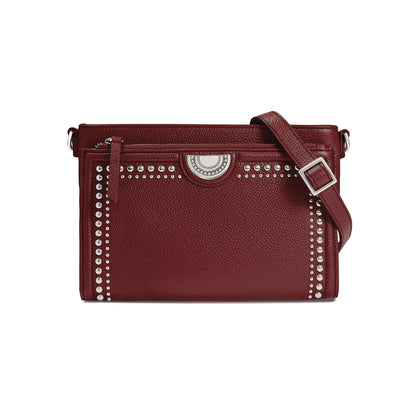 Brighton crossbody handbag in burgundy leather with silver-tone studs, medallion accent, and adjustable strap on a white background