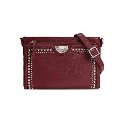 Brighton crossbody handbag in burgundy leather with silver-tone studs, medallion accent, and adjustable strap on a white background