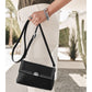Model with a Brighton black leather handbag with silver-tone studded trim and round medallion clasp