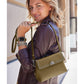 Model with a Brighton olive green shoulder handbag featuring silver studded trim and round medallion clasp
