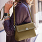Model with a Brighton olive green leather handbag featuring crystal stud trim and silver-tone medallion accent