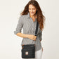 Model with a Brighton black quilted crossbody handbag featuring heart stitching, leather trim, and adjustable strap