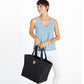 Model with a Brighton black quilted tote handbag featuring heart pattern, dual handles, and small logo patch