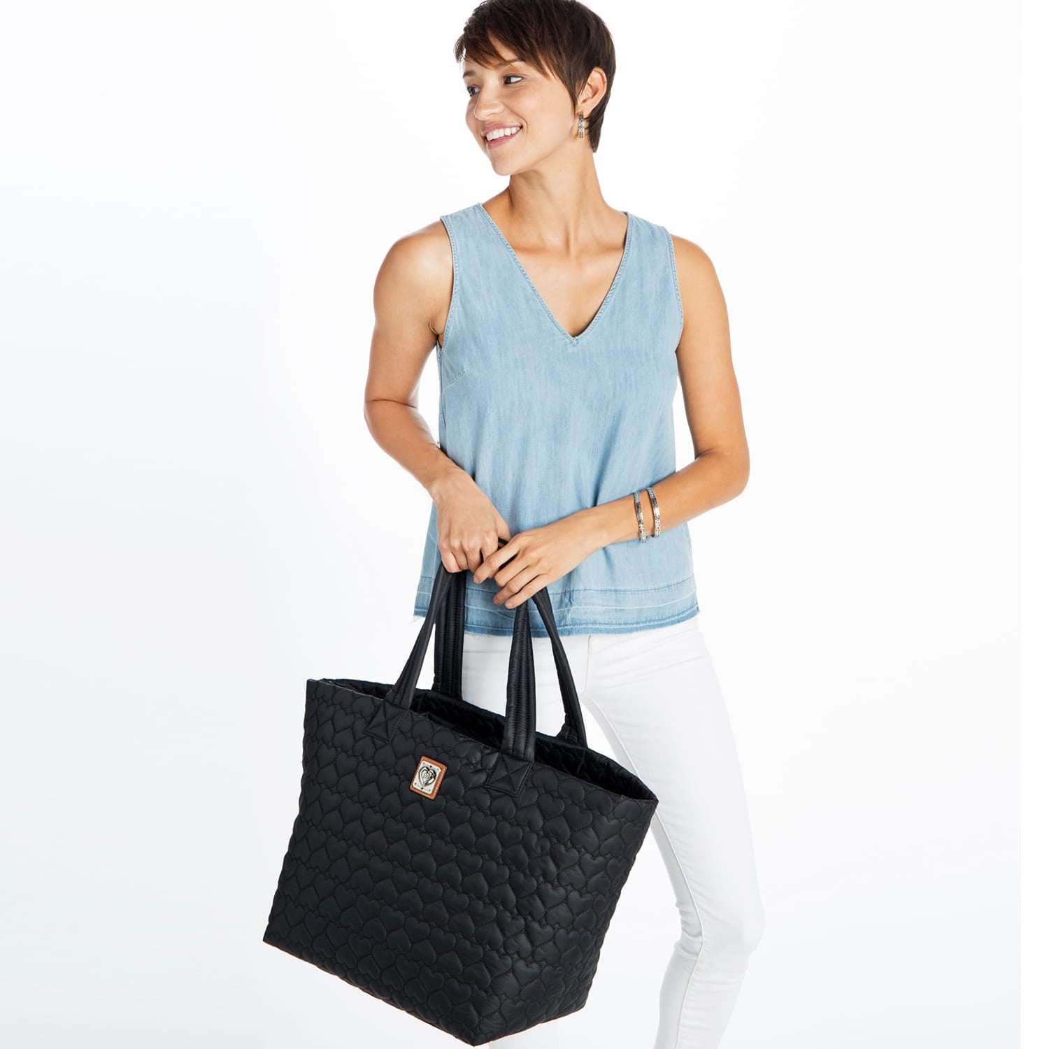 Model with a Brighton black quilted tote handbag featuring heart pattern, dual handles, and small logo patch