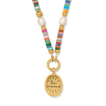 Brighton beaded pendant necklace with multicolored stones, pearls, gold-plated accents, and Be Present oval charm on a white background