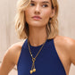 Model wearing a Brighton gold-plated lariat necklace with dual heart charms and crystal accents, paired with hoop earrings