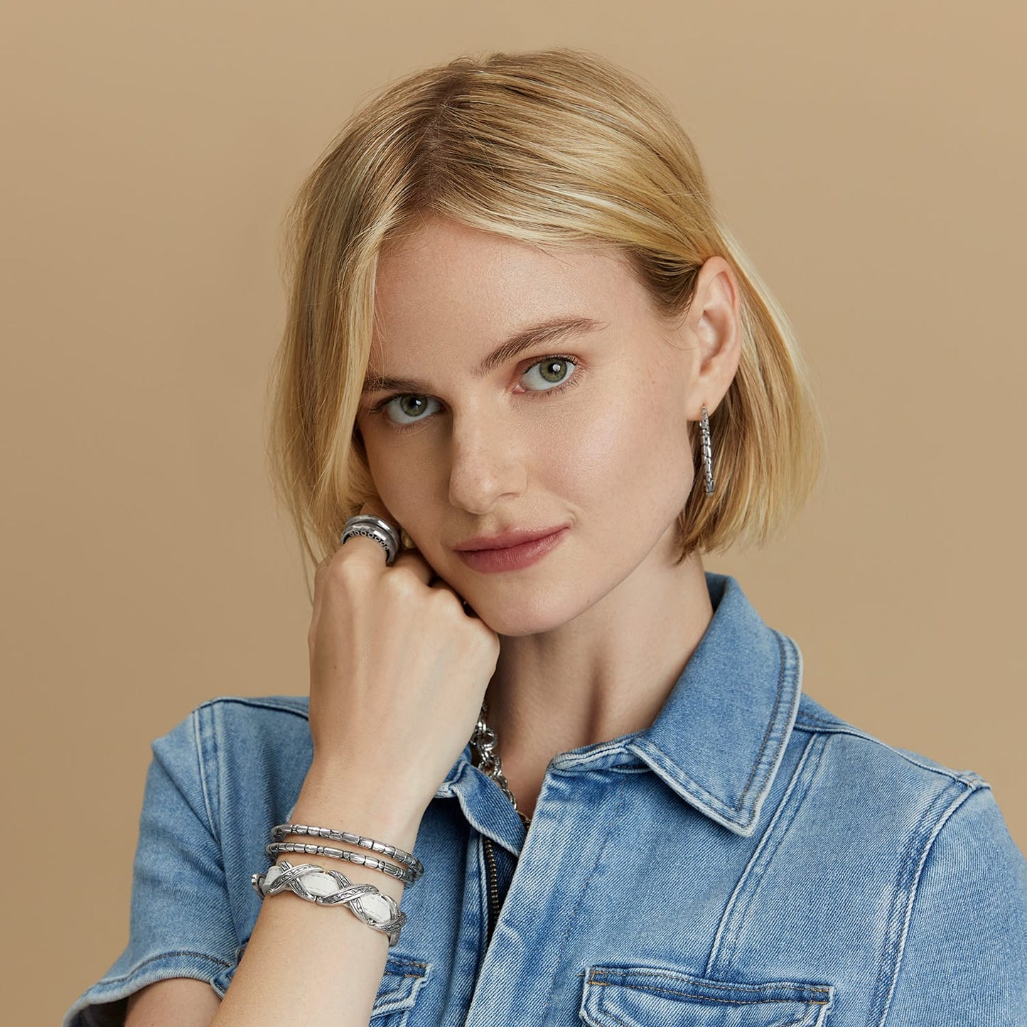Model wearing Brighton silver-plated hoop earrings with stacked textured bracelets and a band ring.