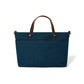 Brighton blue denim handbag shown from the back with brown leather top handles and front pocket on a white background