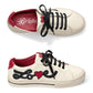 Brighton white leather sneakers with black laces, red heel accents, and embroidered Love script with heart on a white background