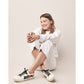 Model wearing Brighton ivory leather sneakers with black laces, red heart accents, and Love script embroidery