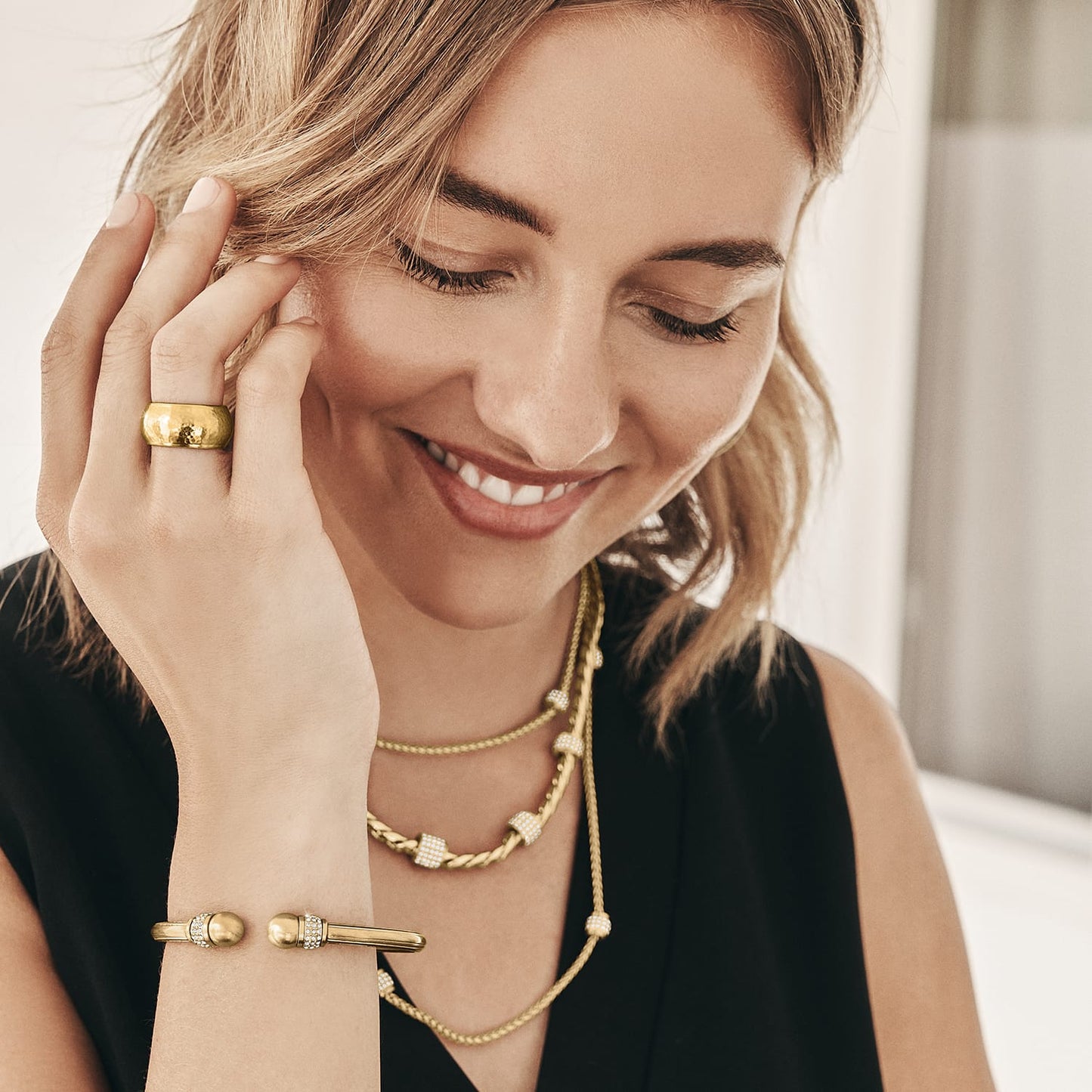 Model wearing a Brighton brushed gold plated ring with hammered band and coordinating Brighton accessories