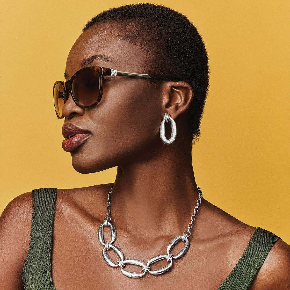 Model wearing Brighton silver-plated chain link necklace paired with matching hammered silver-plated hoop earrings and tortoise sunglasses