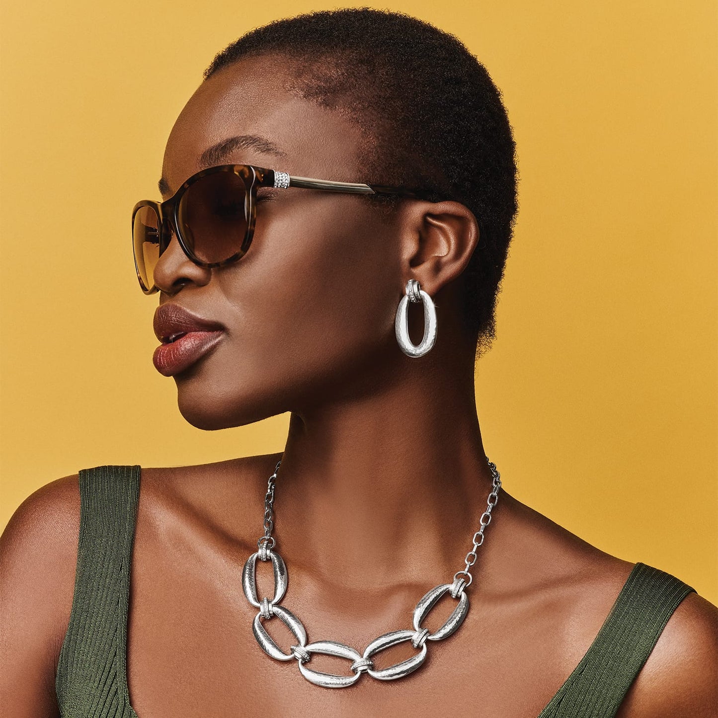 Model wearing Brighton silver-plated chain link necklace paired with matching hammered silver-plated hoop earrings and tortoise sunglasses