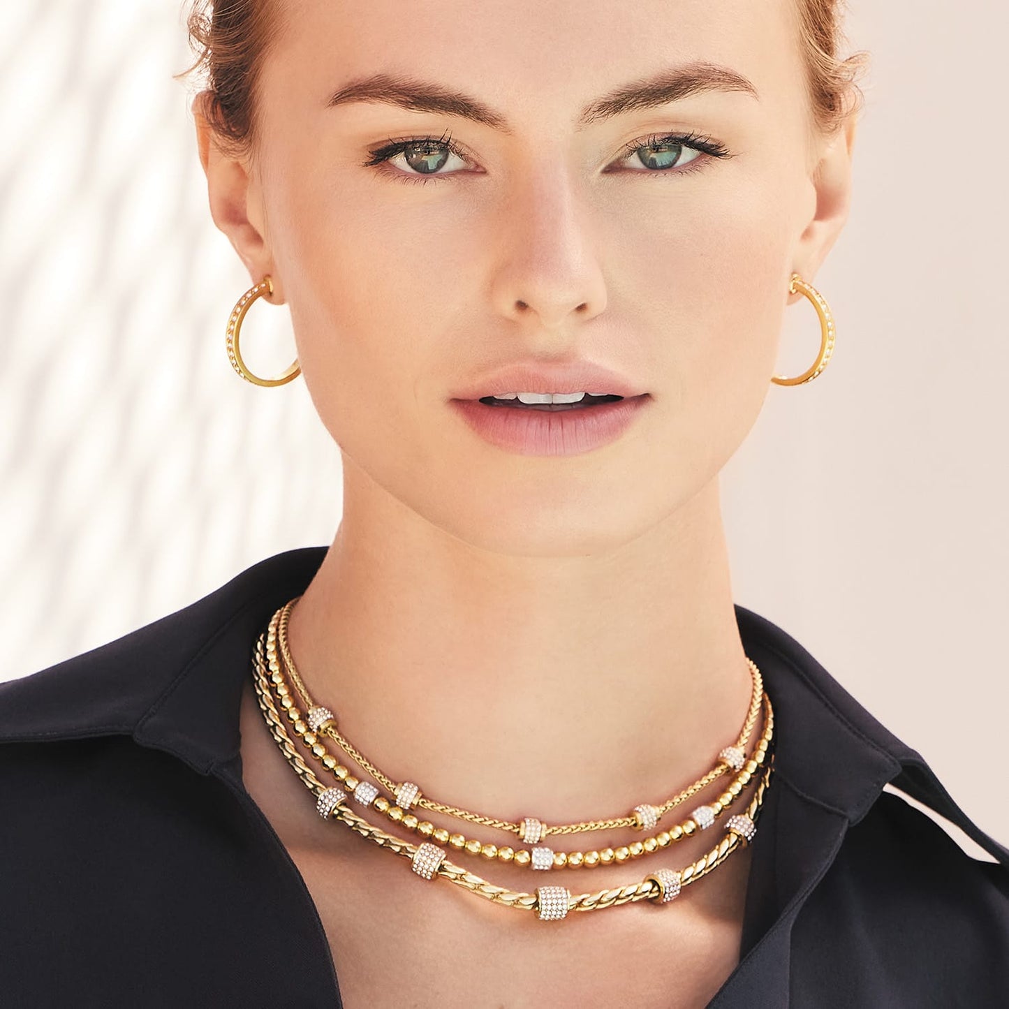 Model wearing Brighton gold-plated layered necklaces with crystal stations paired with matching gold-plated hoop earrings