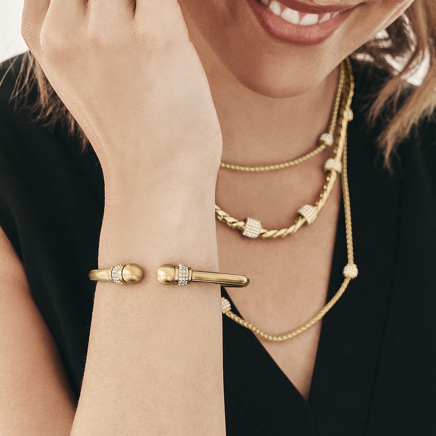 Model wearing a Brighton gold-plated hinged bangle bracelet with crystal accents and coordinating Brighton accessories