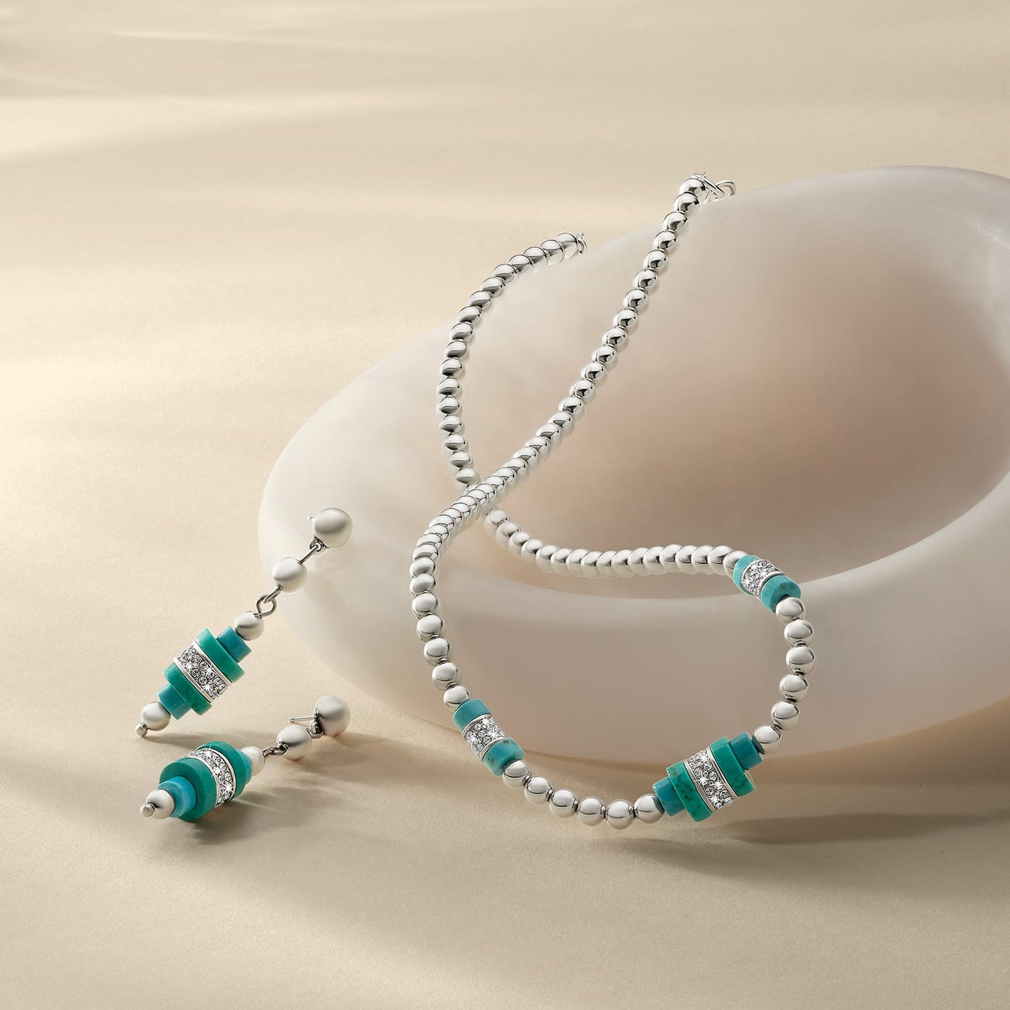 Brighton silver-plated beaded necklace and drop earrings with turquoise beads and crystal accents, styled with a ceramic dish