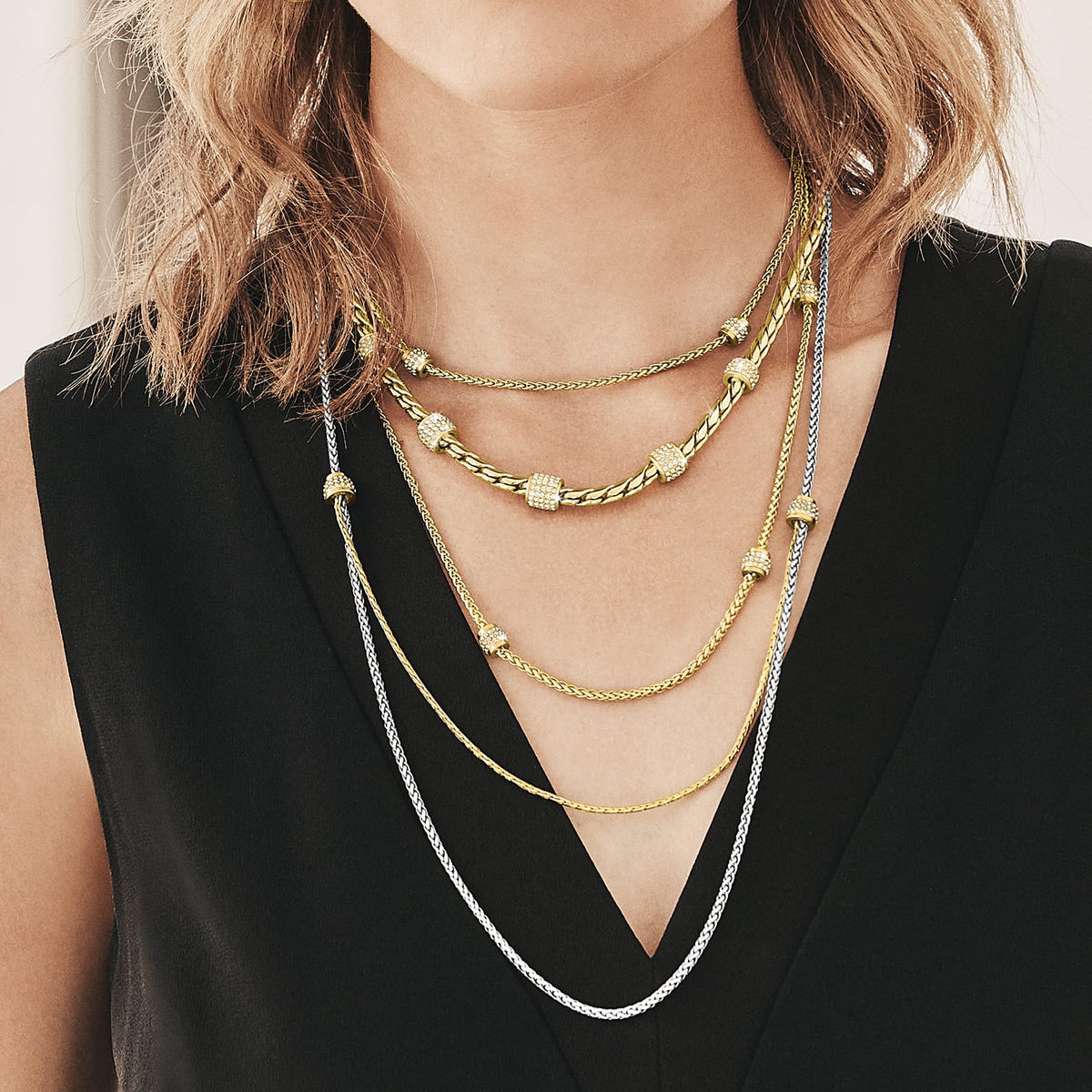 Model wearing layered Brighton two-tone necklaces with crystal-accented stations in silver and gold chain styles