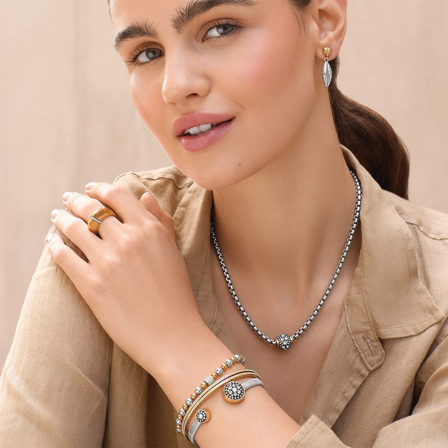 Model wearing a Brighton two-tone box chain necklace with crystal bead pendant and coordinating Brighton accessories